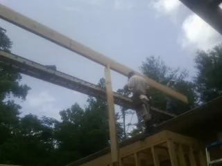 Carpenter setting a ridge beam over a new addition frame — Ice Dam Removal by Roofing Brothers in Curtis