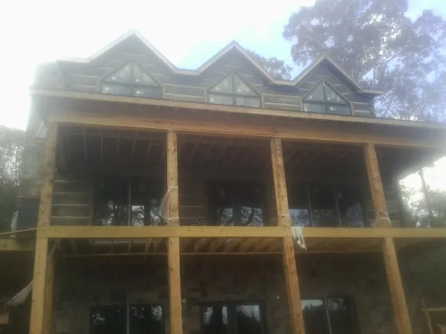 Dormers and porch framing on a large log home under construction — Roof Coating work by our crew in Curtis